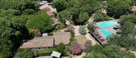 Vista aèria d'una zona residencial amb diverses cases, una piscina i vegetació als voltants.