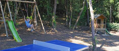 Un patio de juegos con tobogán, columpios y una casita de madera.