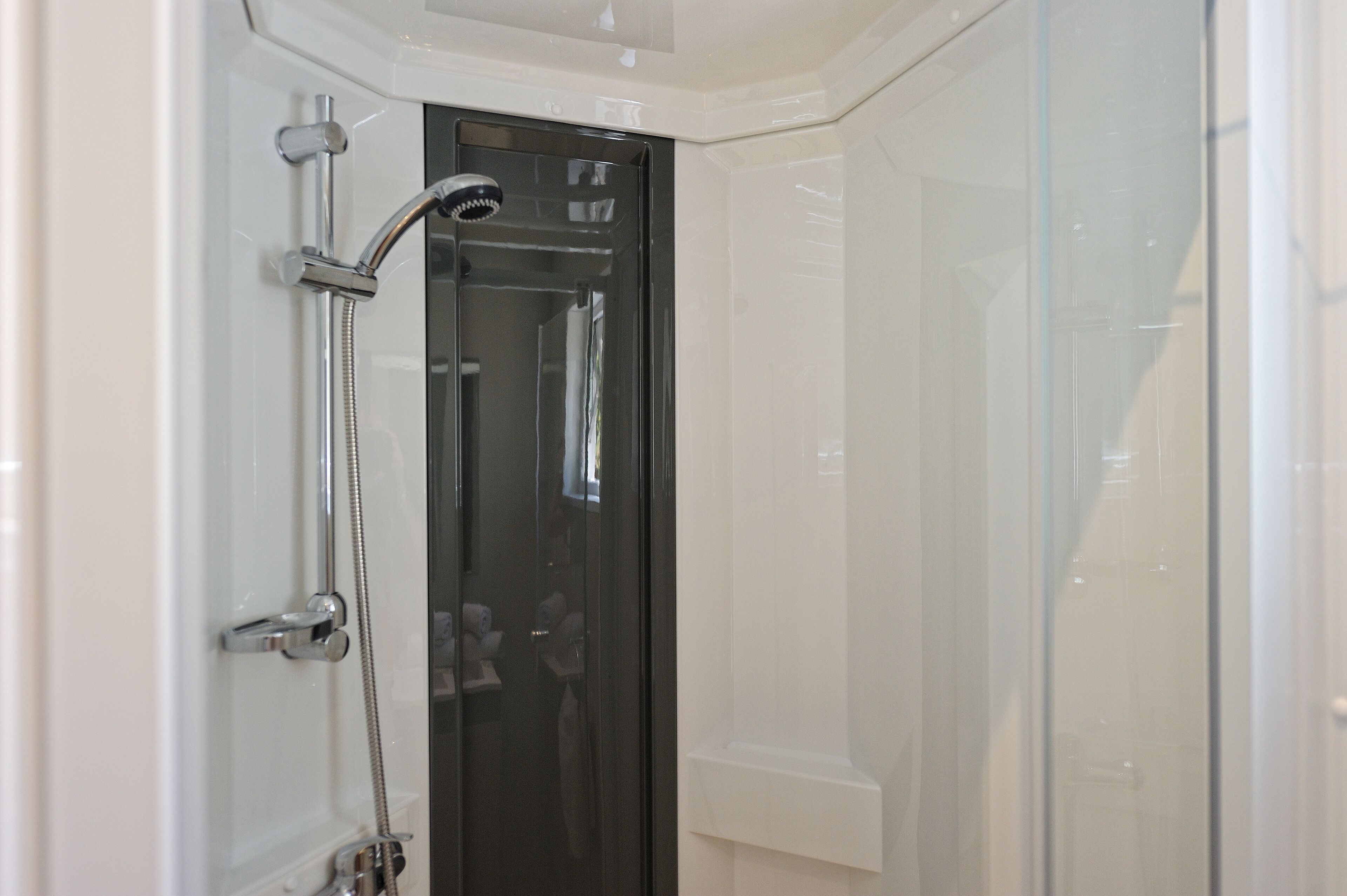 Un baño moderno con cabina de ducha de vidrio, ducha visible y puerta con manija.