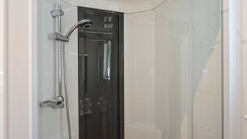 Un baño moderno con cabina de ducha de vidrio, ducha visible y puerta con manija.
