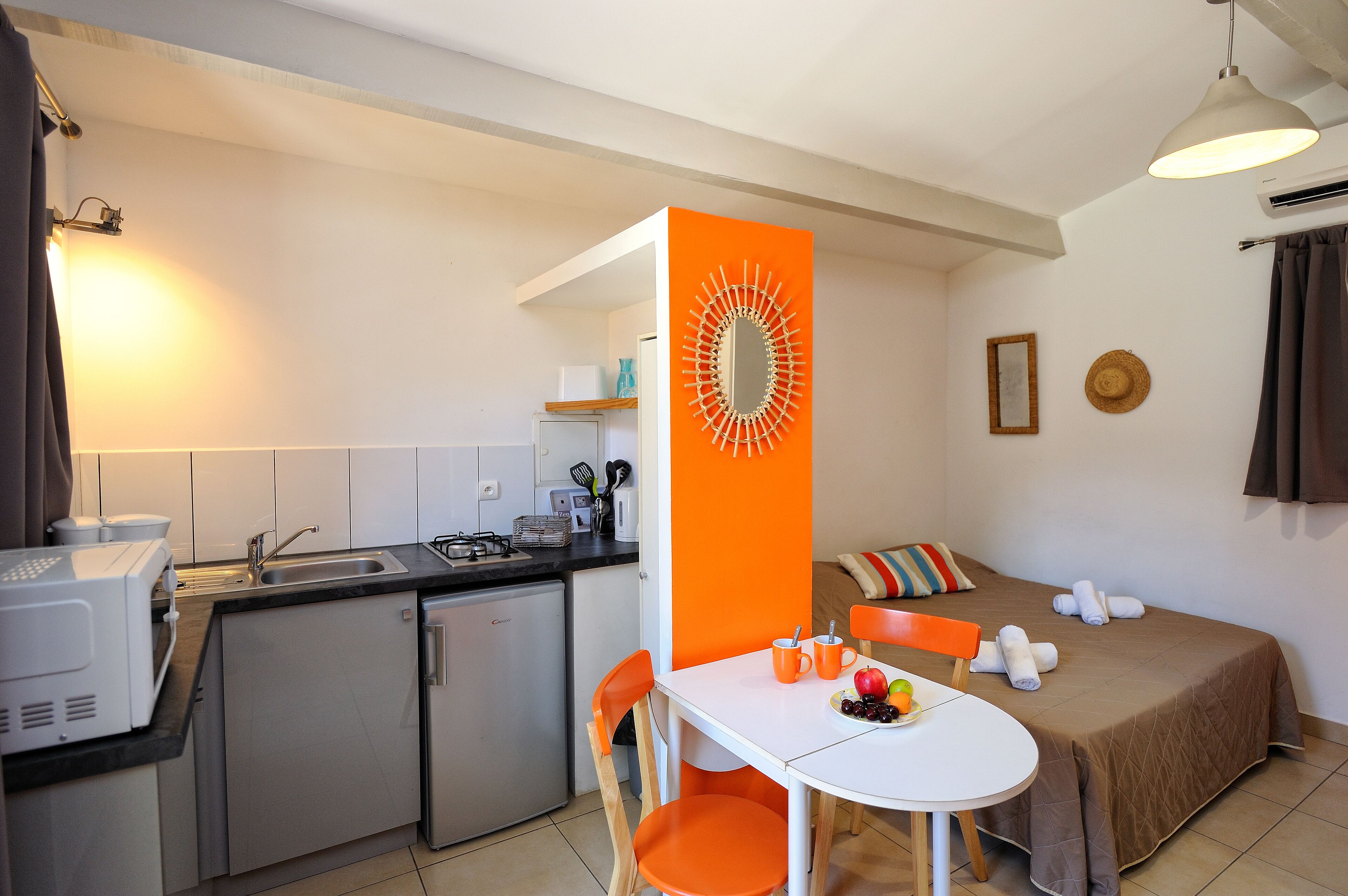 Une chambre d’hôtel compacte comprenant un coin cuisine, un espace repas et un lit.