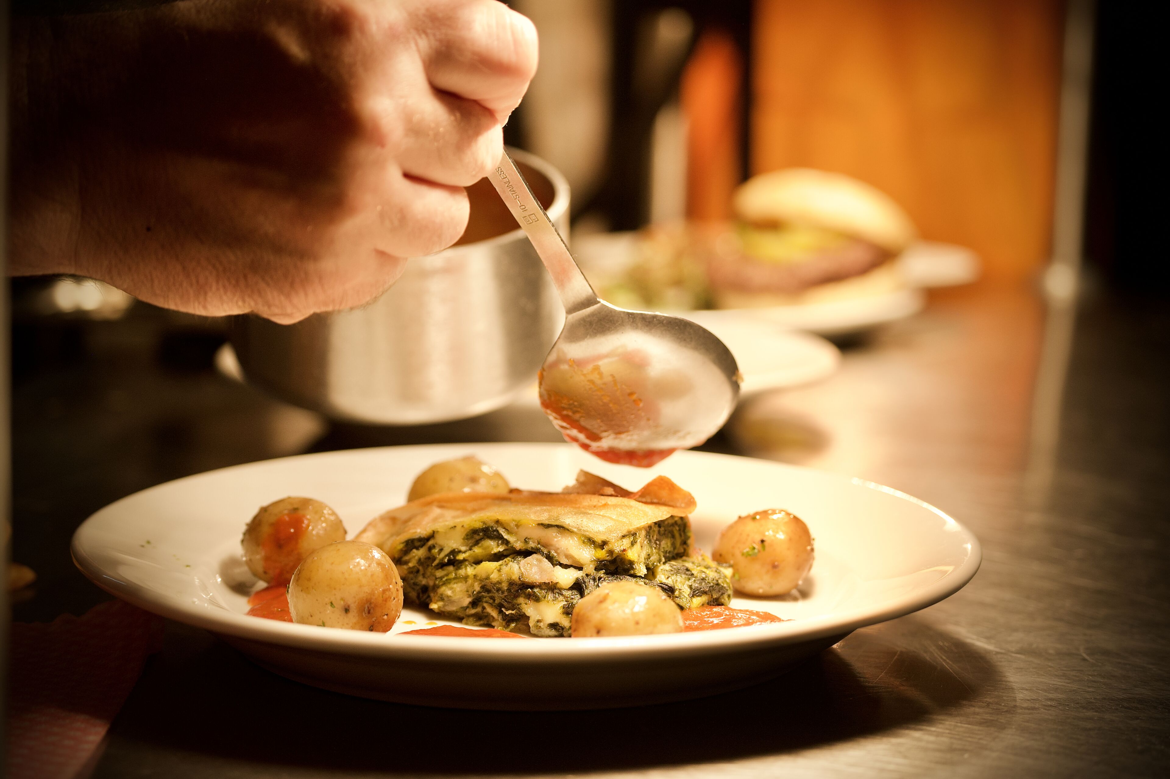 A hand serving food on a plate.