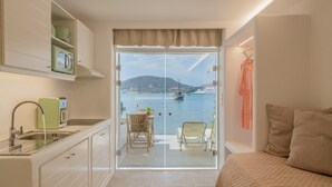 A modern room with a balcony, a bed, a sink, and a view of the sea. - Heliotropio Studios & Apartments (Milos)