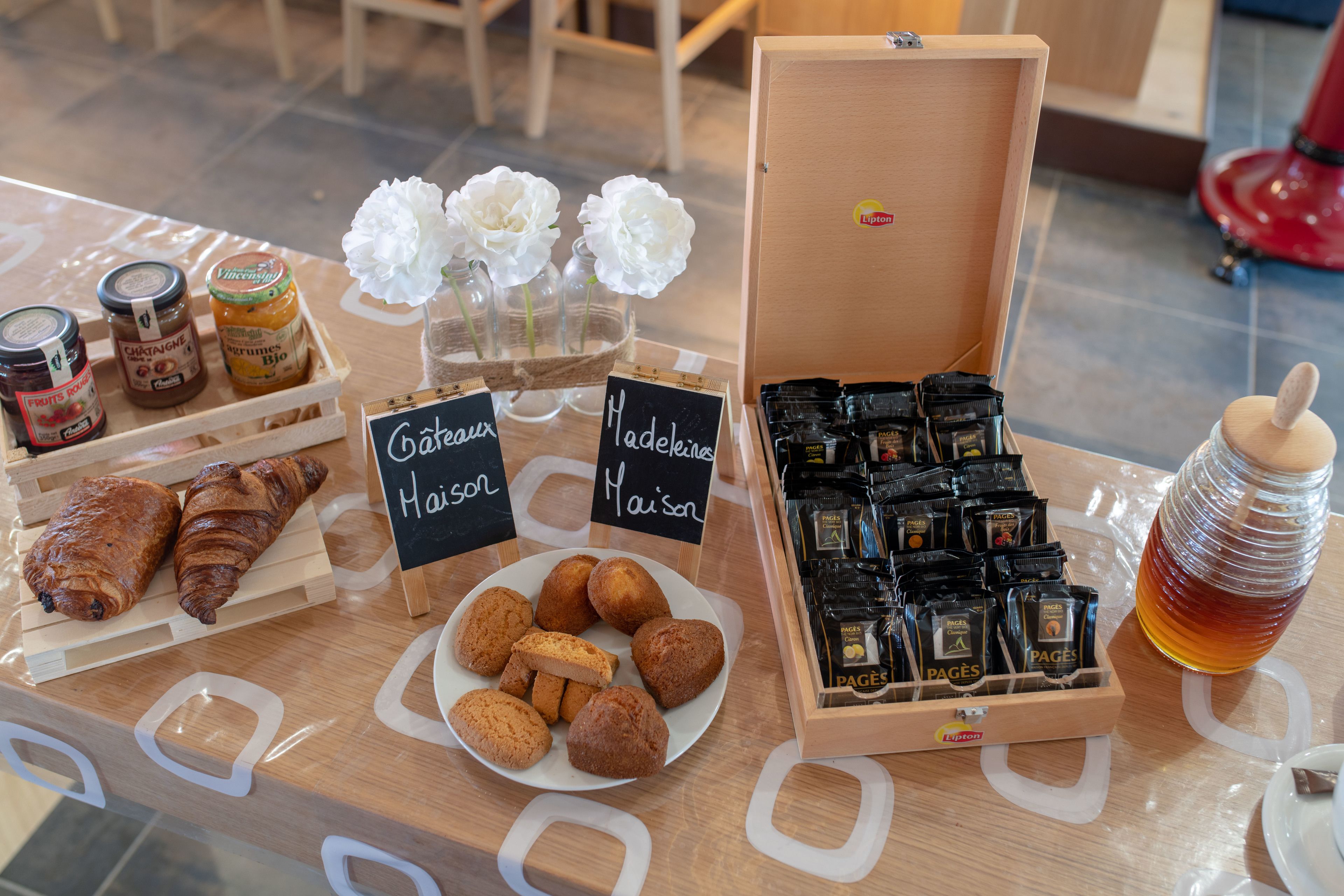 A display of pastries, coffee, and flowers on a wooden table.