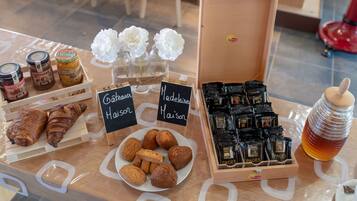 A display of pastries, coffee, and flowers on a wooden table.
