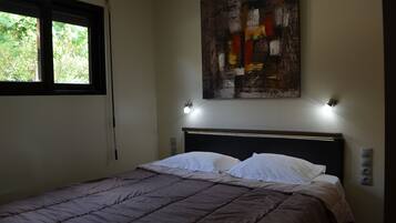 A bedroom with a bed, a window, and a wall-mounted abstract painting.