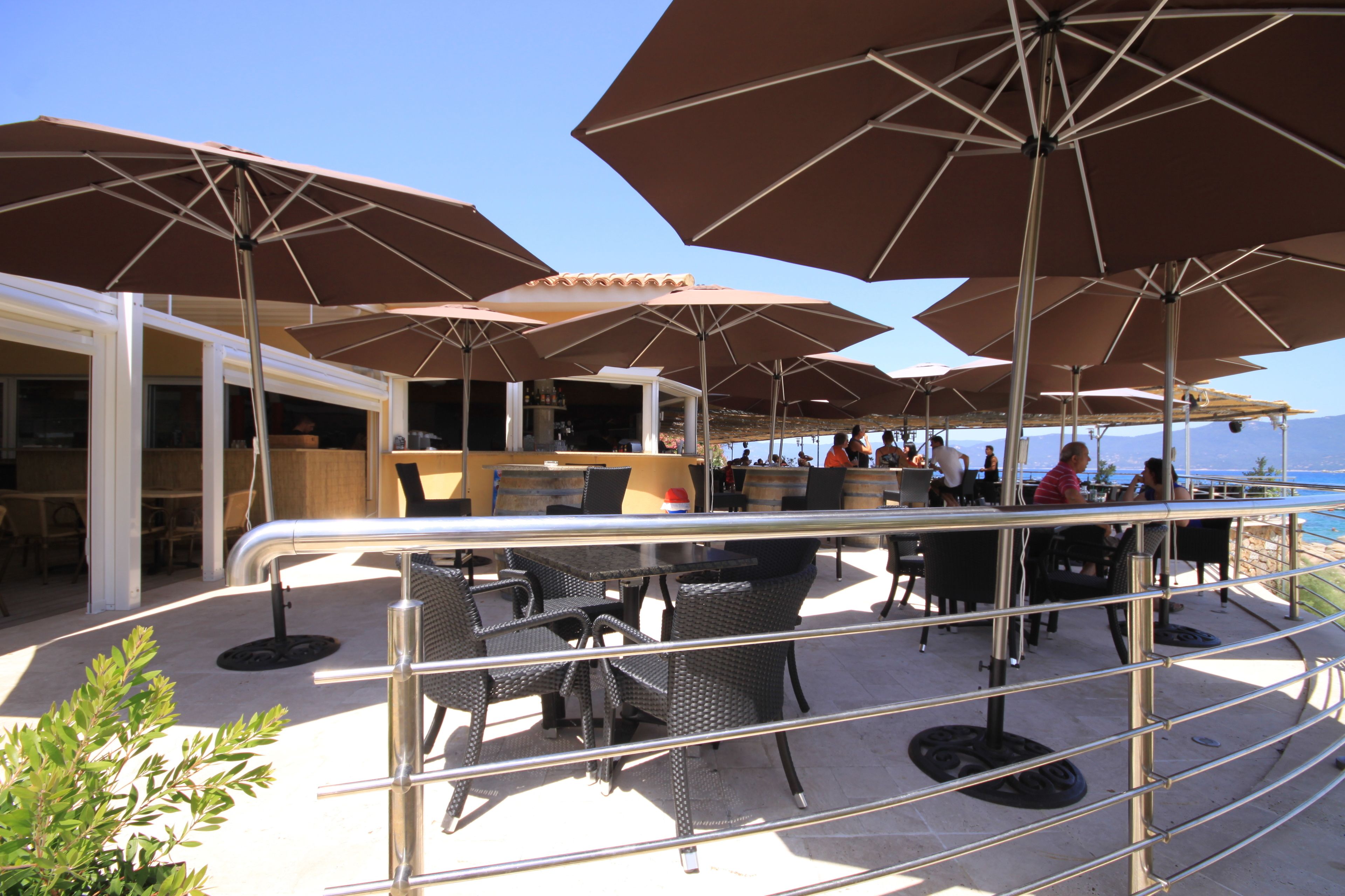 Un espace de restauration en plein air, doté de plusieurs tables et chaises, et entouré de grands parasols.