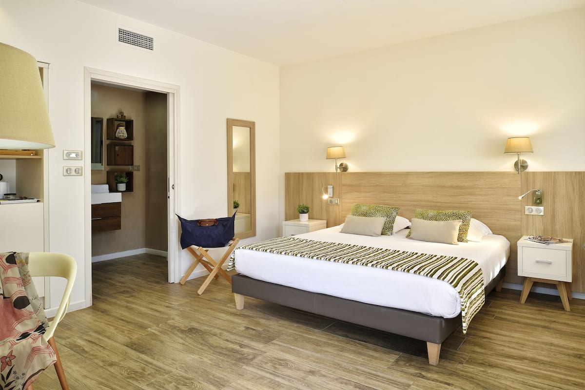 Un dormitorio moderno con una cama grande, mesitas de noche, una silla y un armario.