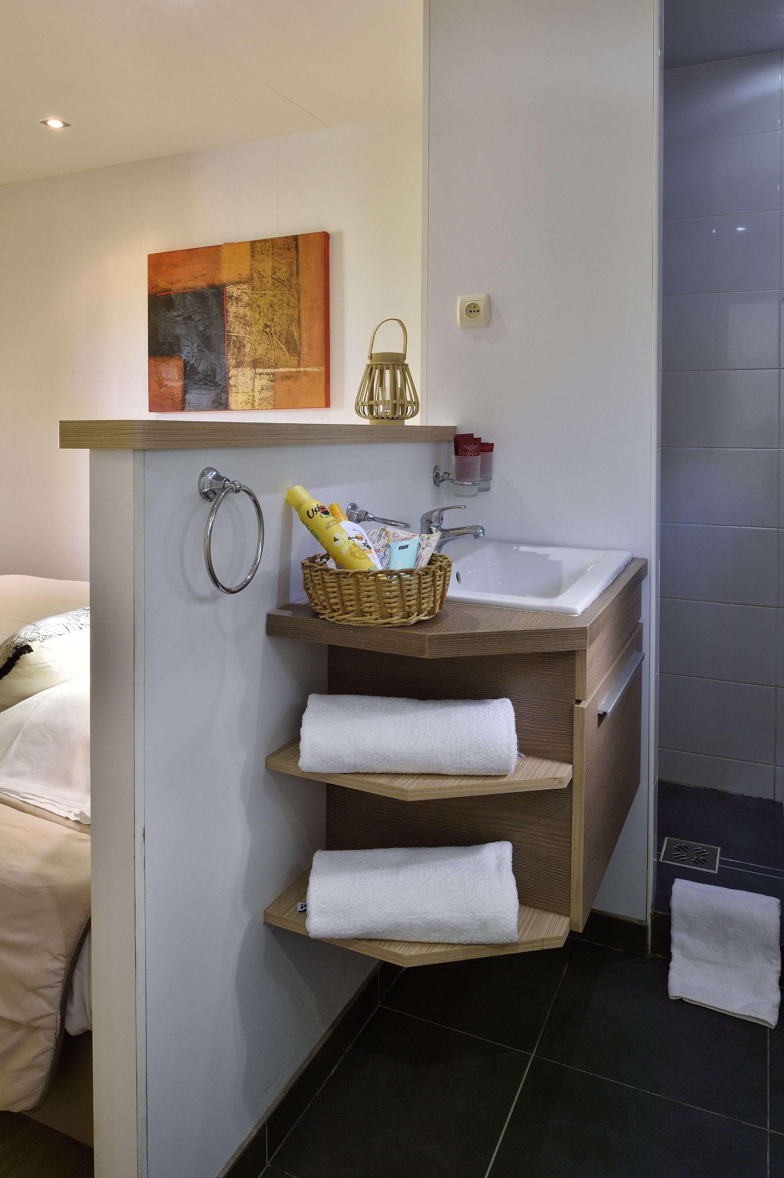 Un baño moderno con tocador de madera, lavamanos blanco y toallero.