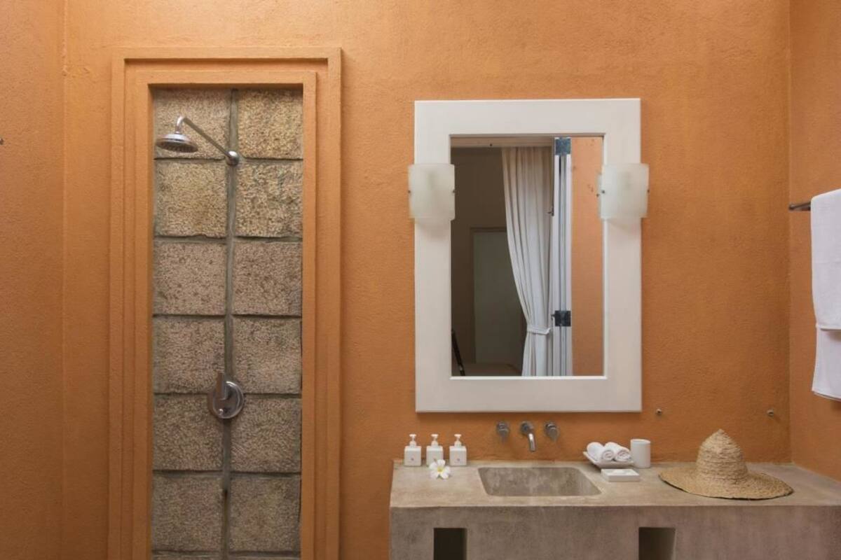 A bathroom with a shower, a sink with toiletries, and a mirror.