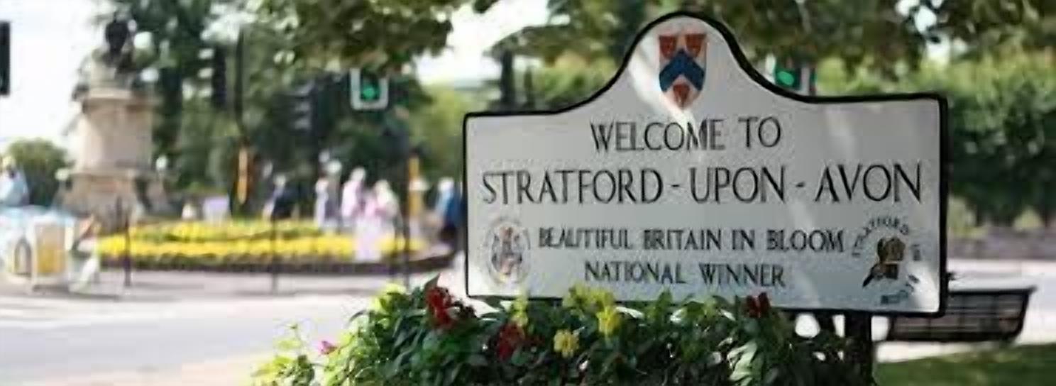 Un letrero de bienvenida para Stratford-upon-Avon con un logotipo y texto que indica que es un ganador a nivel nacional.