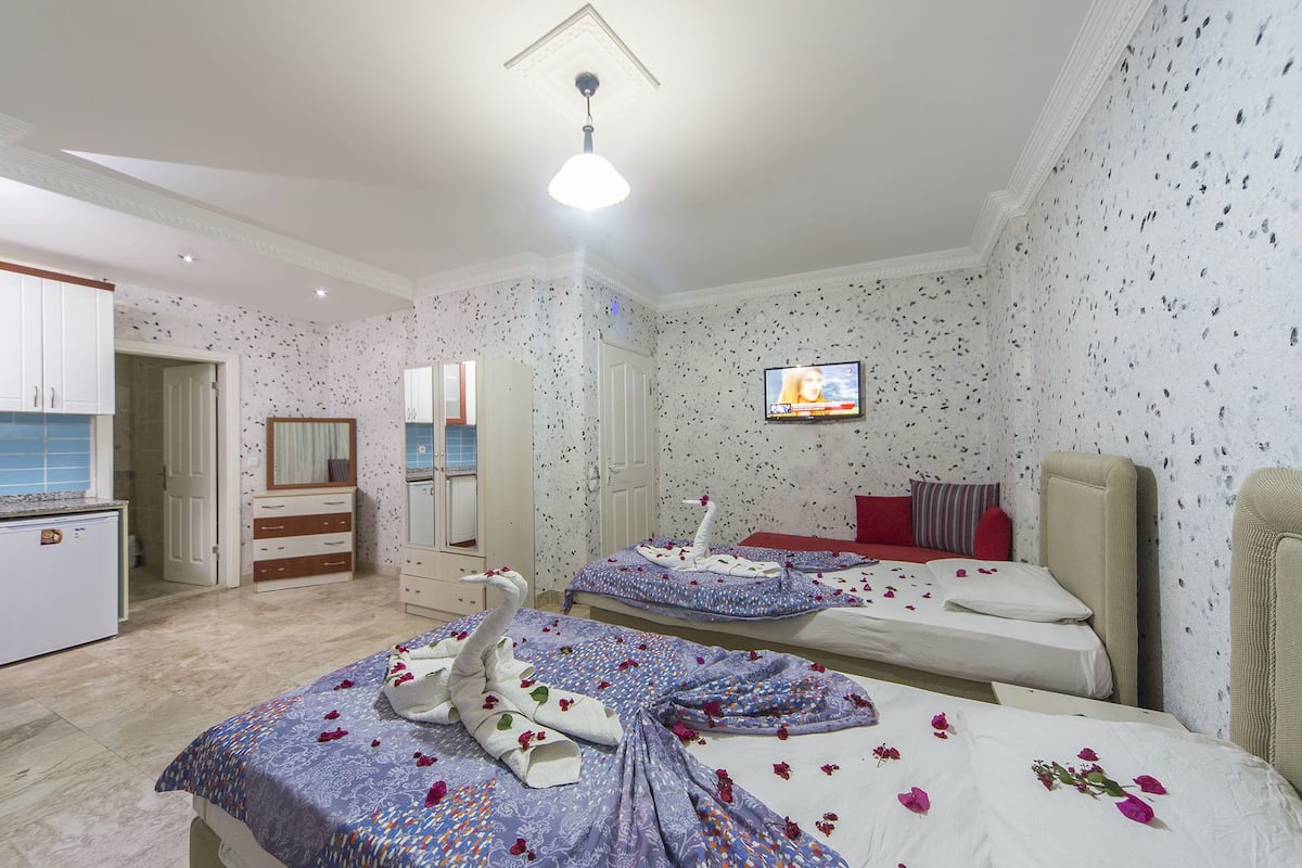 A hotel room with two beds, a TV, a wardrobe, and a bathroom.