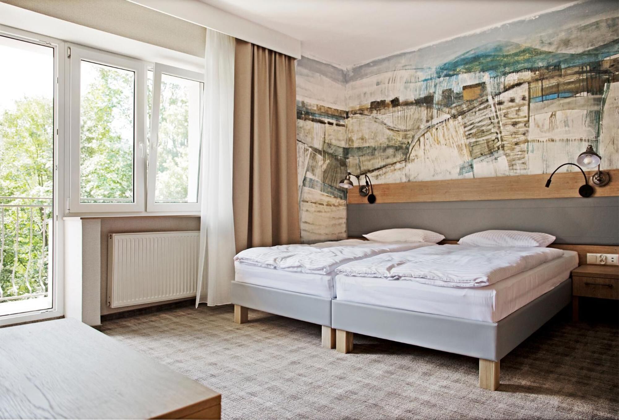 A bedroom with a bed, a nightstand, a window, and a radiator.
