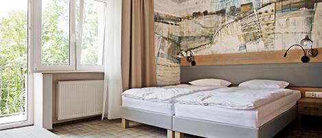 A bedroom with a bed, a nightstand, a window, and a radiator.