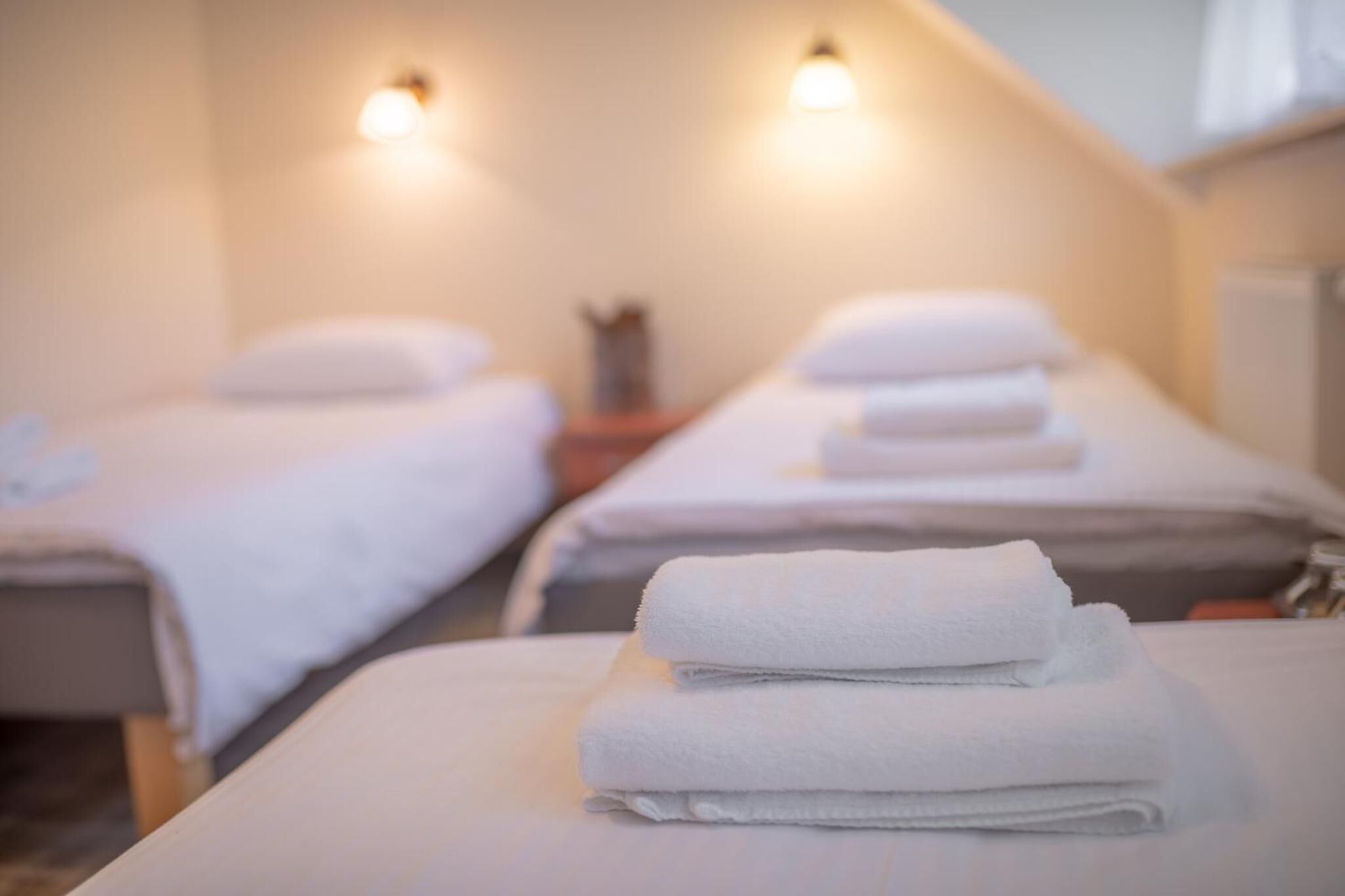 A room with two beds, each with a neatly folded white towel.