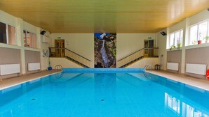 An indoor swimming pool with a waterfall mural, wooden railings, and potted plants. - Dom Wczasowy Beskidy (Wisla)