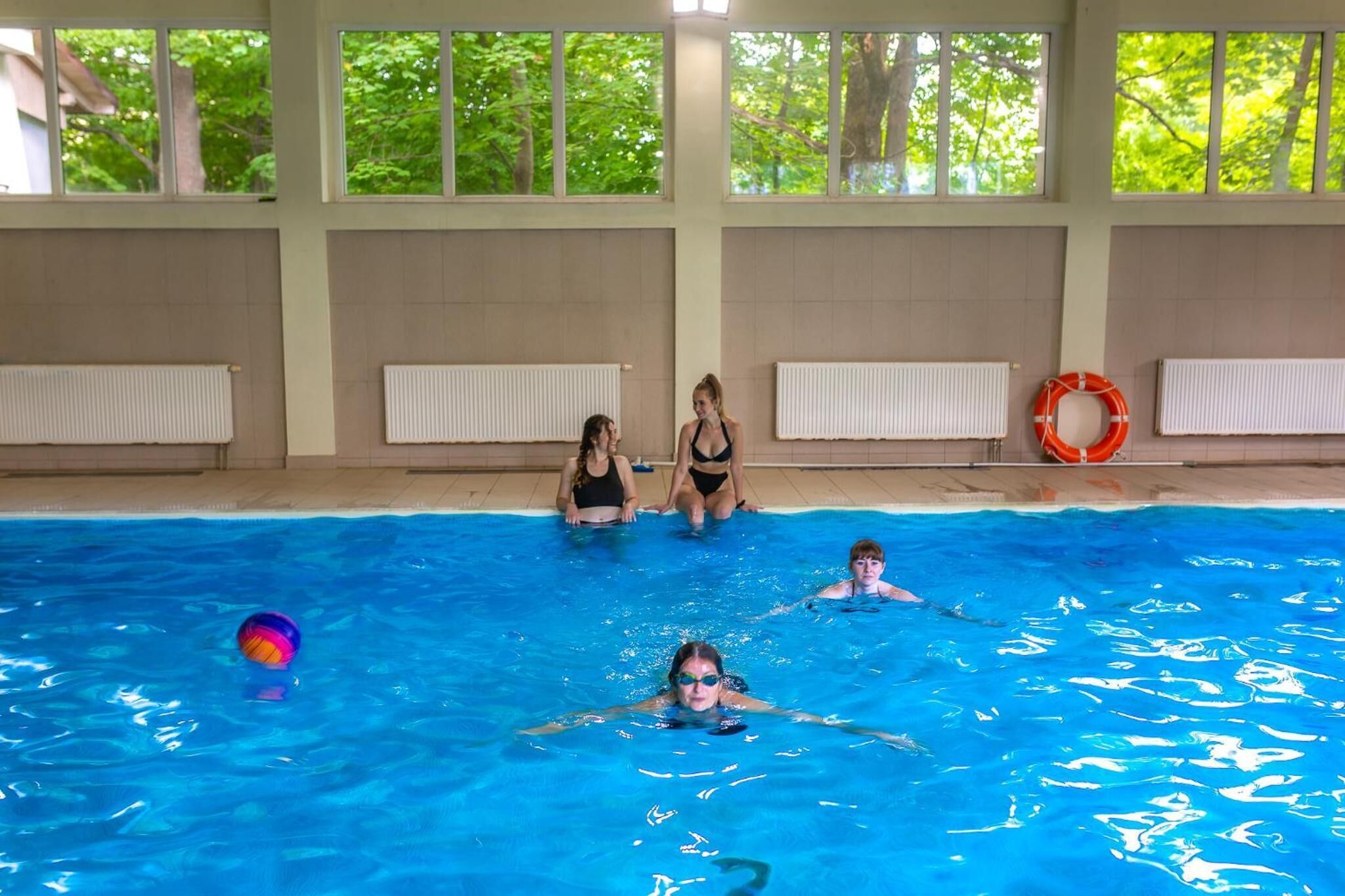 An indoor swimming pool with clear windows, tiled walls, and a lifebuoy.