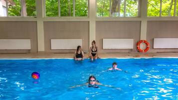 An indoor swimming pool with clear windows, tiled walls, and a lifebuoy.