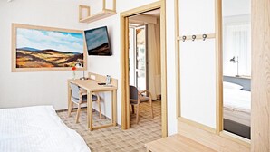 A hotel room with a bed, a desk, two chairs, a TV, and a wardrobe. - Dom Wczasowy Beskidy (Wisla)
