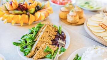 Variedad de alimentos sobre una mesa, incluyendo frutas cortadas, un sándwich y un postre.