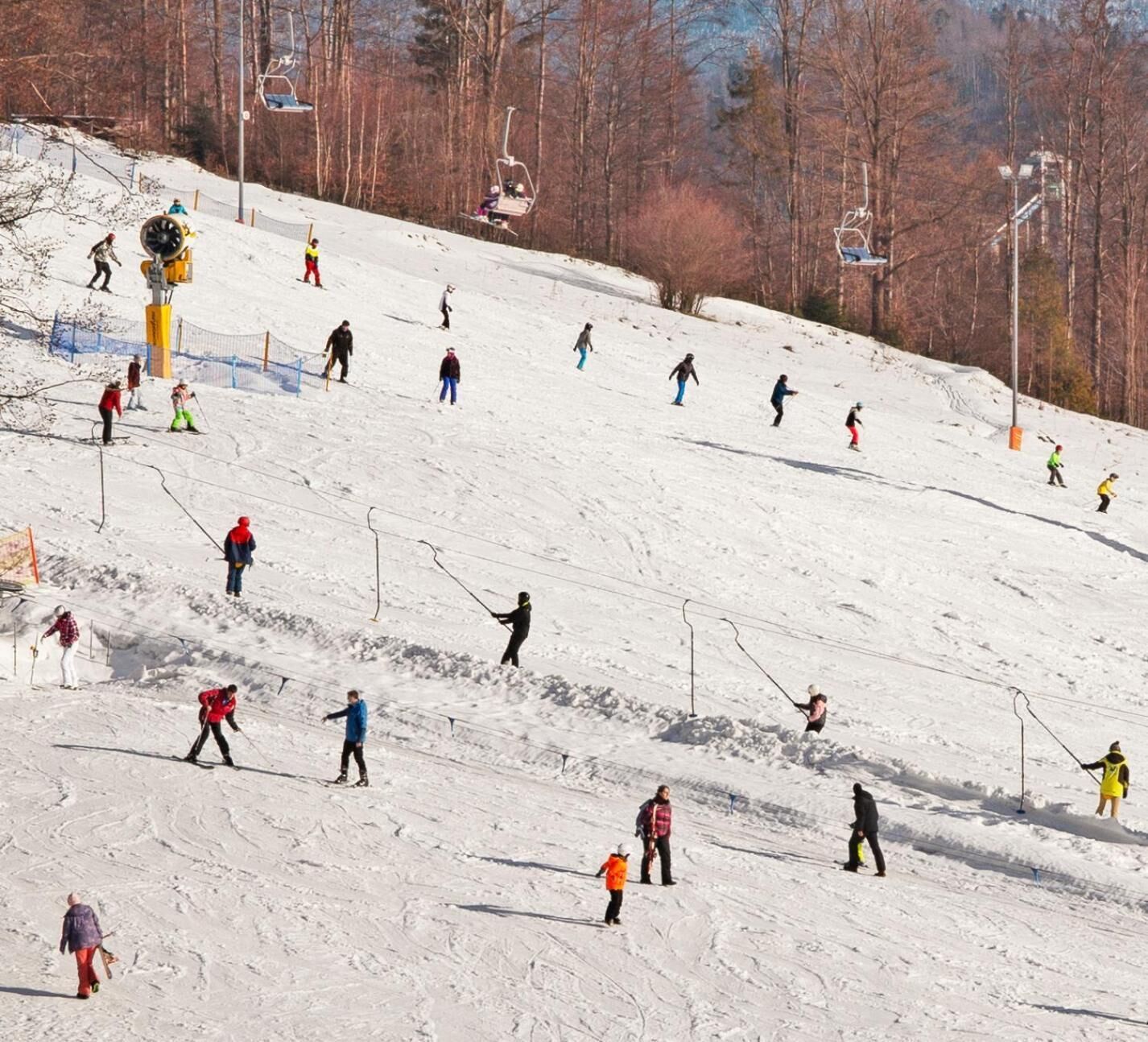 A ski slope with skiers and snowboarders descending.