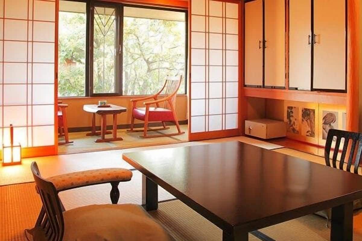 Une pièce de style japonais traditionnel, avec un sol recouvert de tatamis, une table basse, un banc rembourré et des portes coulissantes.