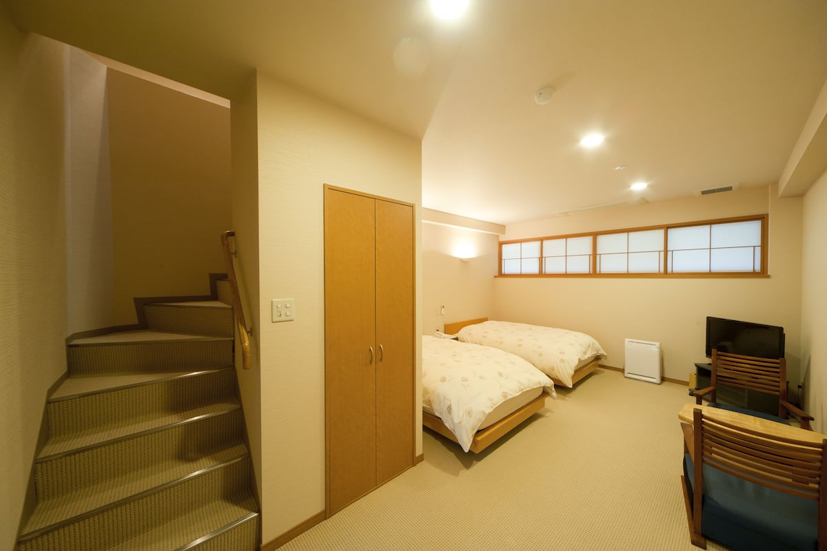 Une chambre avec deux lits, une télévision, un bureau et une fenêtre.