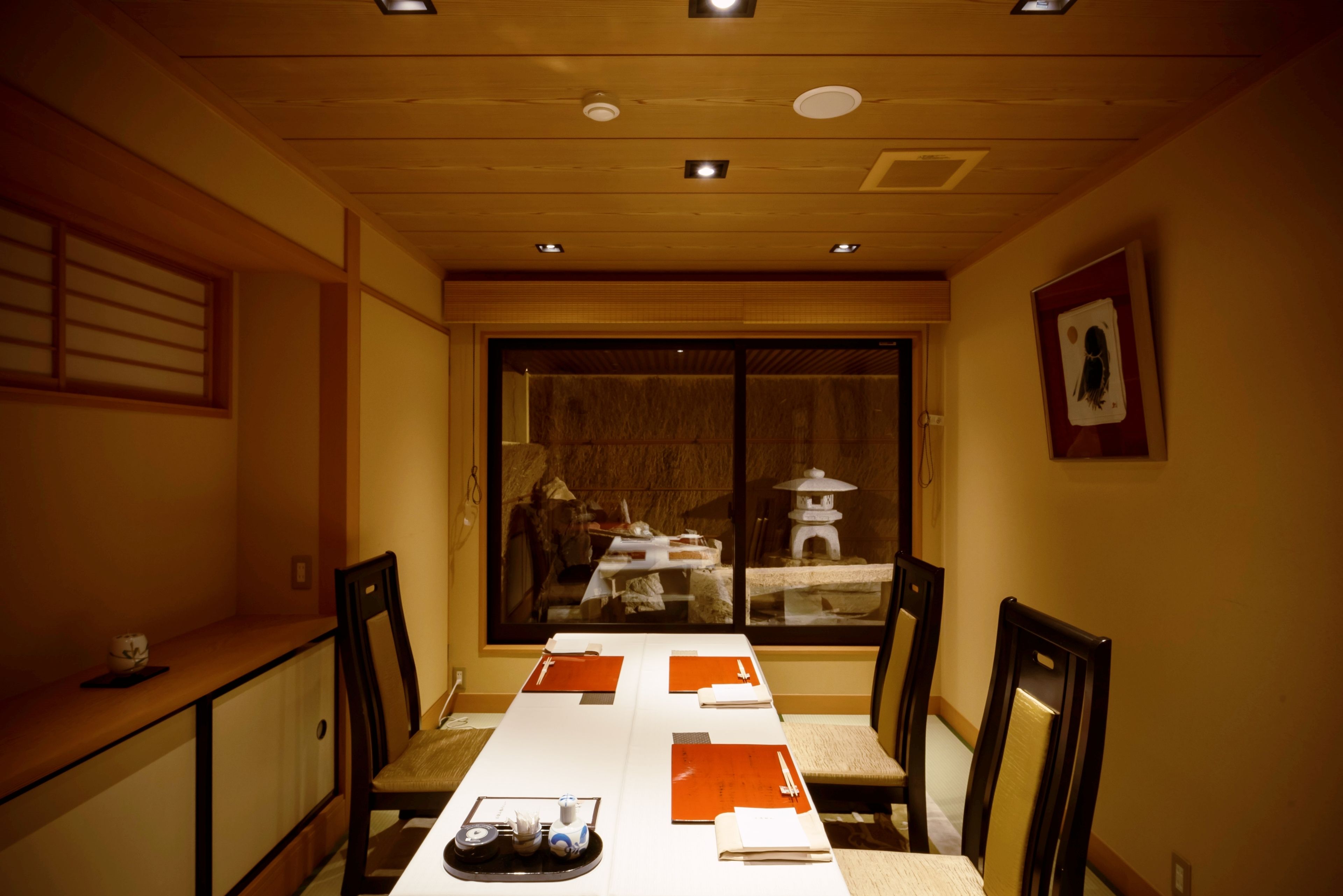 Comedor con una mesa larga, sillas y vistas a través de un ventanal.
