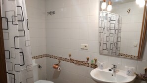Un baño con inodoro, lavamanos y espejo.