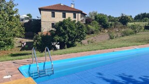Una piscina con tabla de salto, rodeada de césped y un edificio de piedra.