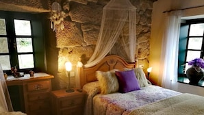 Un dormitorio con pared de piedra, cama con dosel, lámparas de noche y un escritorio con silla.