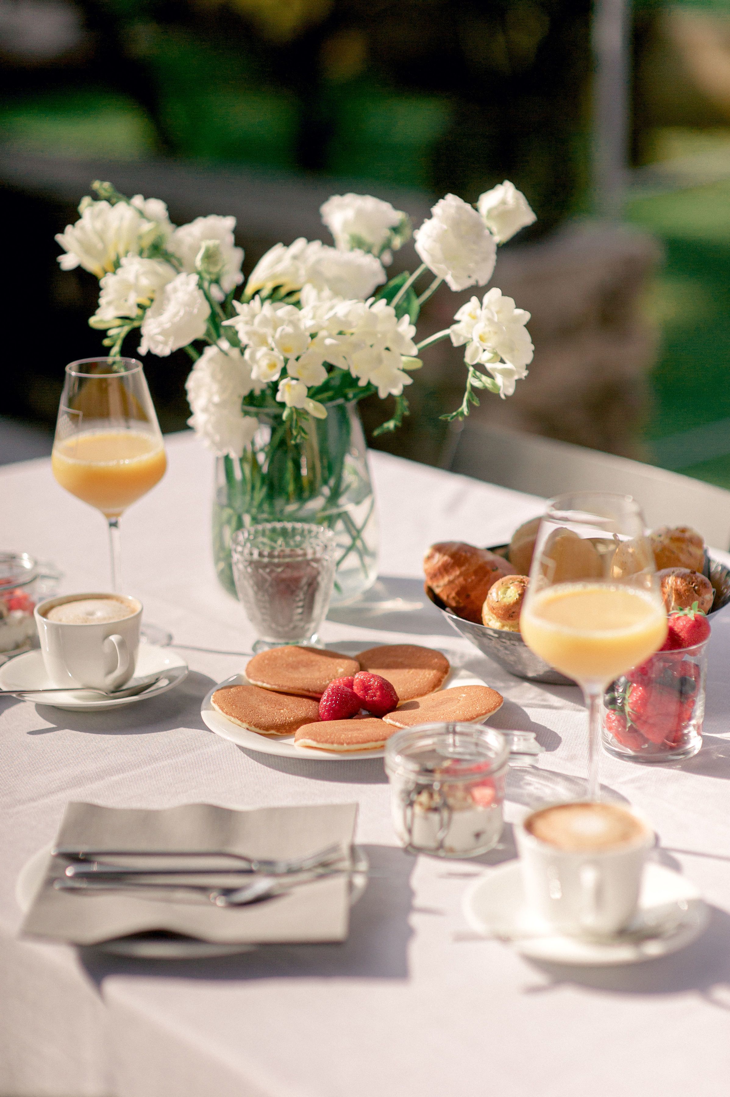 Une table de petit-déjeuner avec des viennoiseries, des fruits et des boissons.
