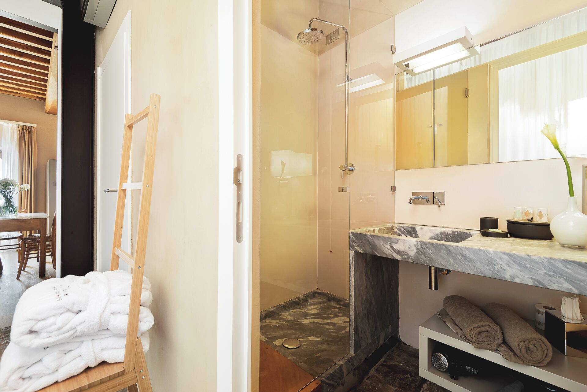 A modern bathroom with a shower, a marble sink, and a mirror.