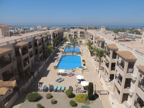 Een resort met een centraal gelegen zwembad, meerdere balkons en uitzicht op zee.
