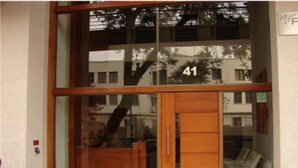 Entrada de un edificio moderno con puerta de vidrio y puerta de madera, con el número 41 a la vista en la pared.