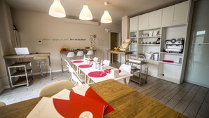 A modern kitchen with white cabinets, a coffee machine, and a dining area with red placemats and white chairs. - B&B Santa Maria Novella (Florence)
