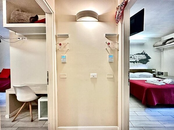 Une chambre d’hôtel avec un lit, un bureau et une chaise. Elle est équipée de commandes murales et d’un téléviseur à écran plat.
