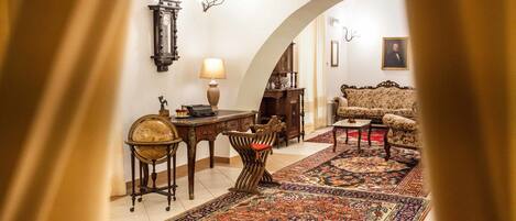 A traditional living room with a patterned rug, a sofa, a table, and a lamp.