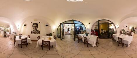 A restaurant with multiple dining areas, each with tables and chairs, and a central glass door entrance.