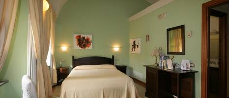 A hotel room with a bed, a desk, a chair, and a nightstand.