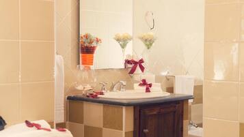 Un baño con lavamanos, espejo y dos arreglos florales en la pared.