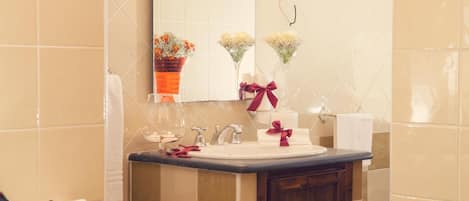 Un baño con lavamanos, espejo y dos arreglos florales en la pared.