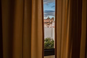 Vista a través de cortinas de un edificio con cúpula y tejado de tejas rojas.