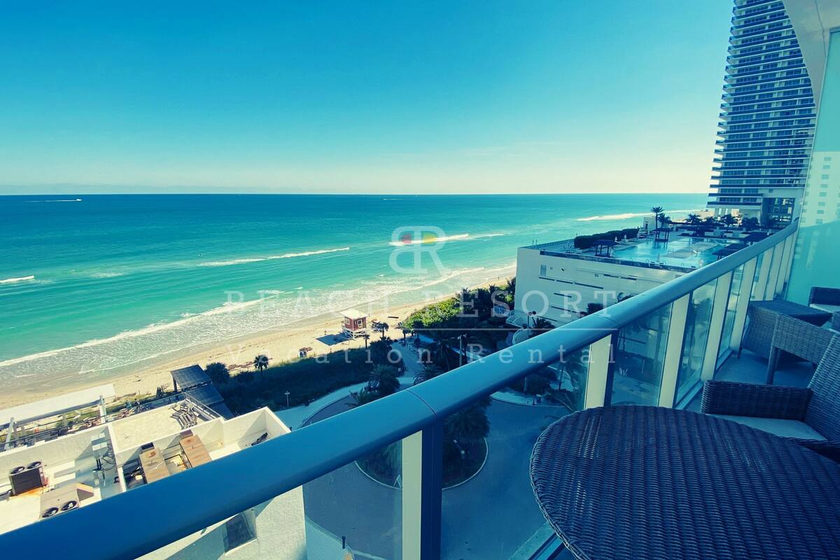 A high-rise hotel with a balcony overlooking a beach and ocean.