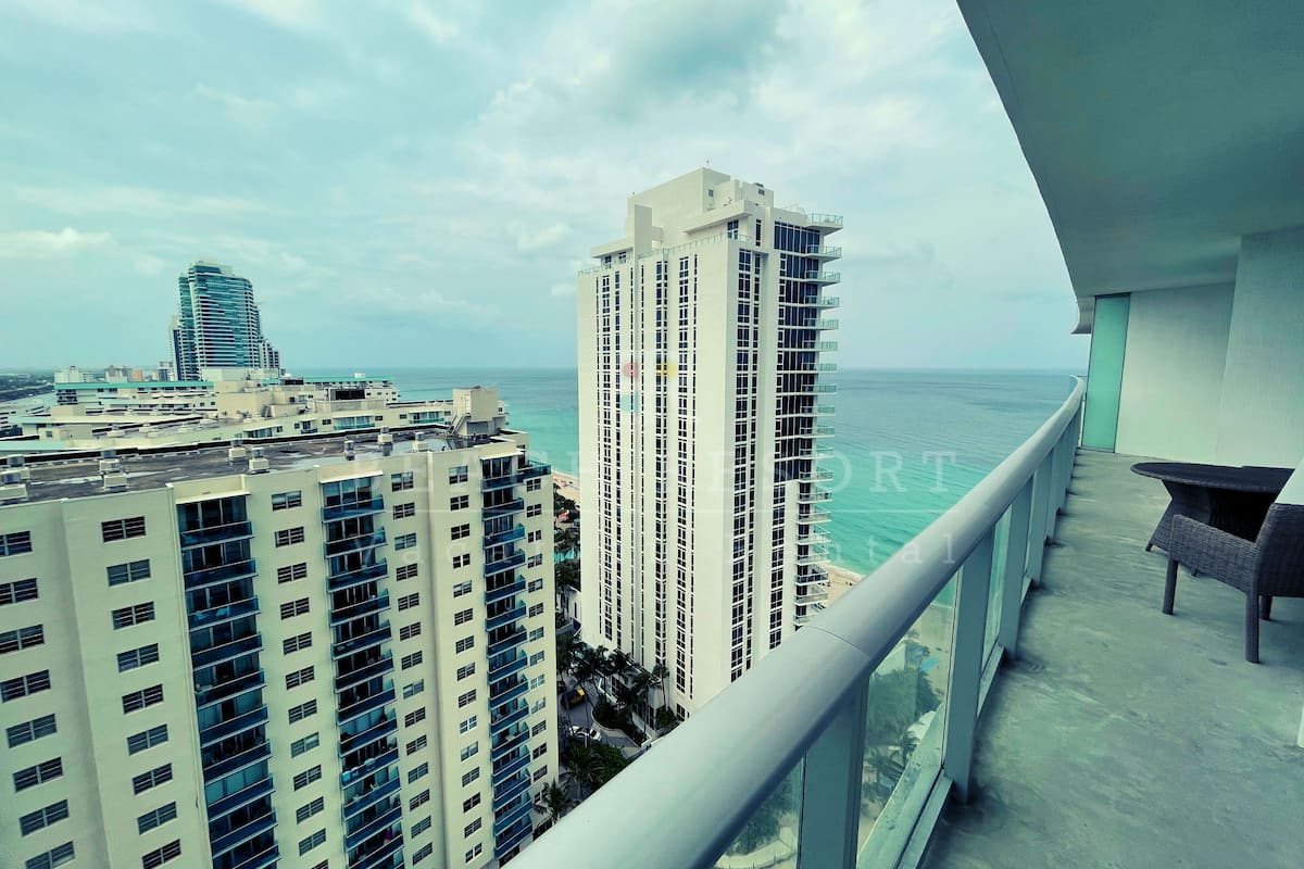 A high-rise building with multiple floors and balconies overlooking a body of water.