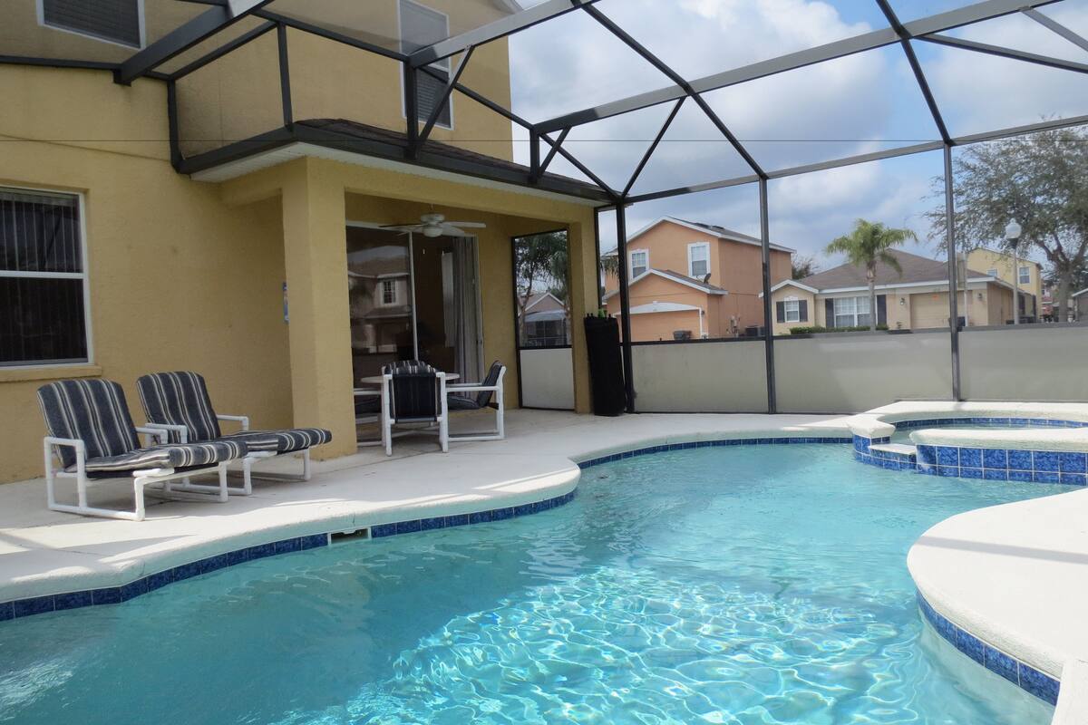 A swimming pool with lounge chairs and a covered patio area.