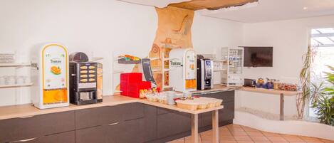 Cozinha moderna com máquinas de café, televisão de tela plana e uma janela grande.