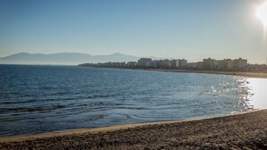 Uma praia com vista clara para o mar e montanhas ao longe.