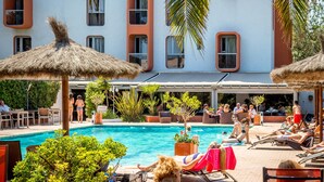 Área da piscina com espreguiçadeiras, guarda-sóis e piscina.