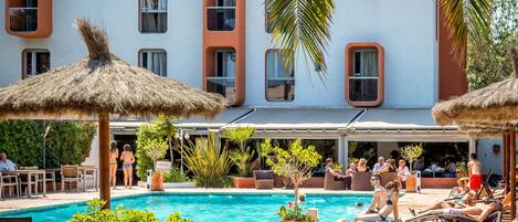 A poolside area with lounge chairs, umbrellas, and a swimming pool.